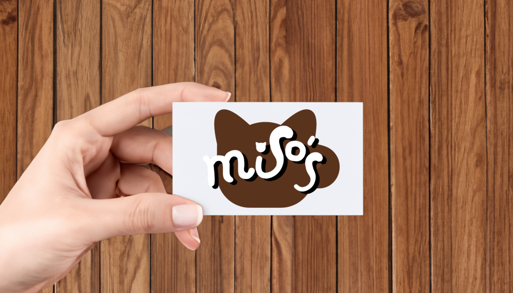 An image a woman holding a business card with a cat cafe logo on it.
