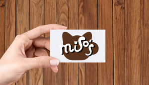 An image a woman holding a business card with a cat cafe logo on it.